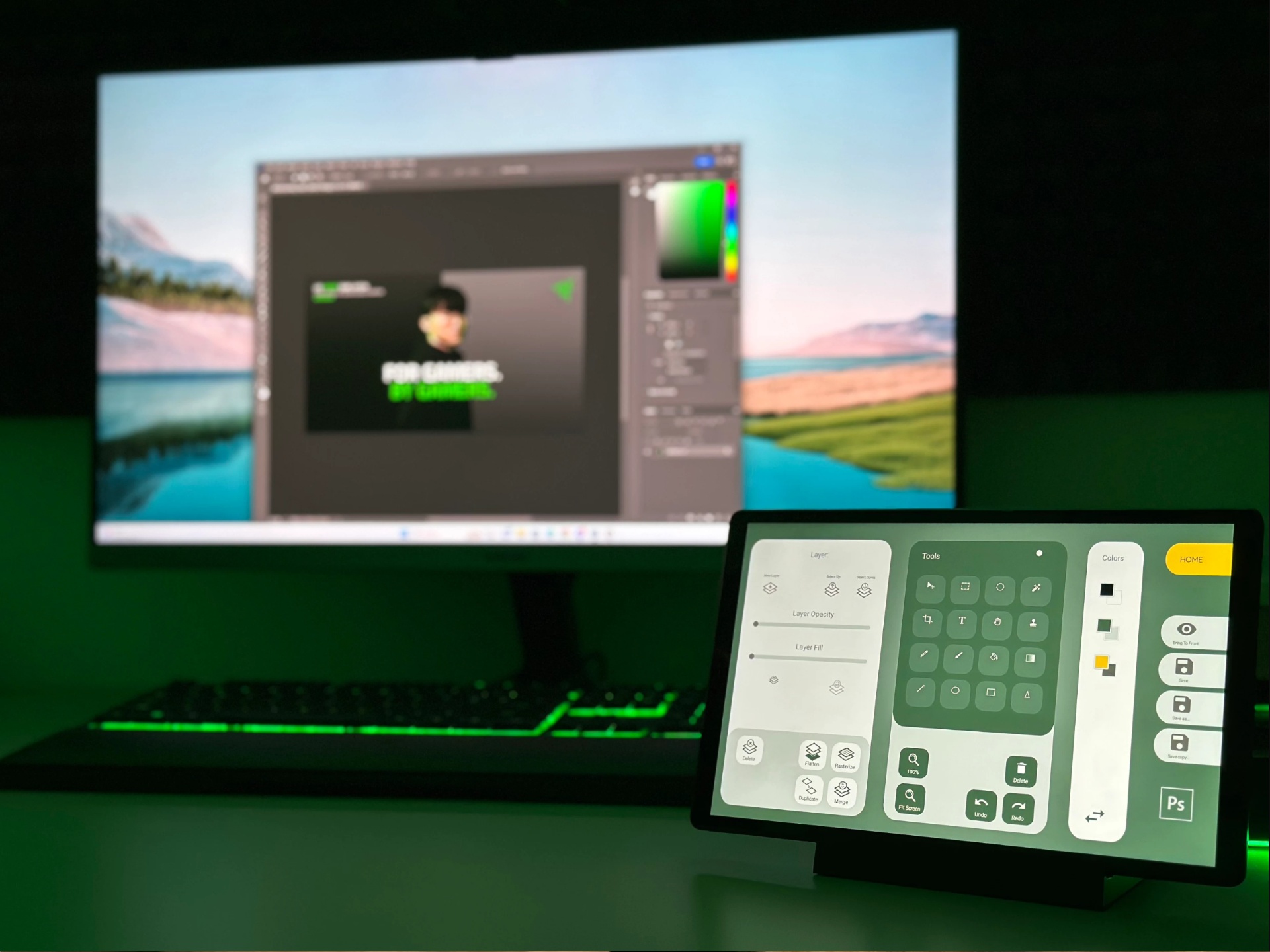 Monitor z grafickým editorem a překryvnými nástroji, na pozadí krajina a zelené rozhraní.