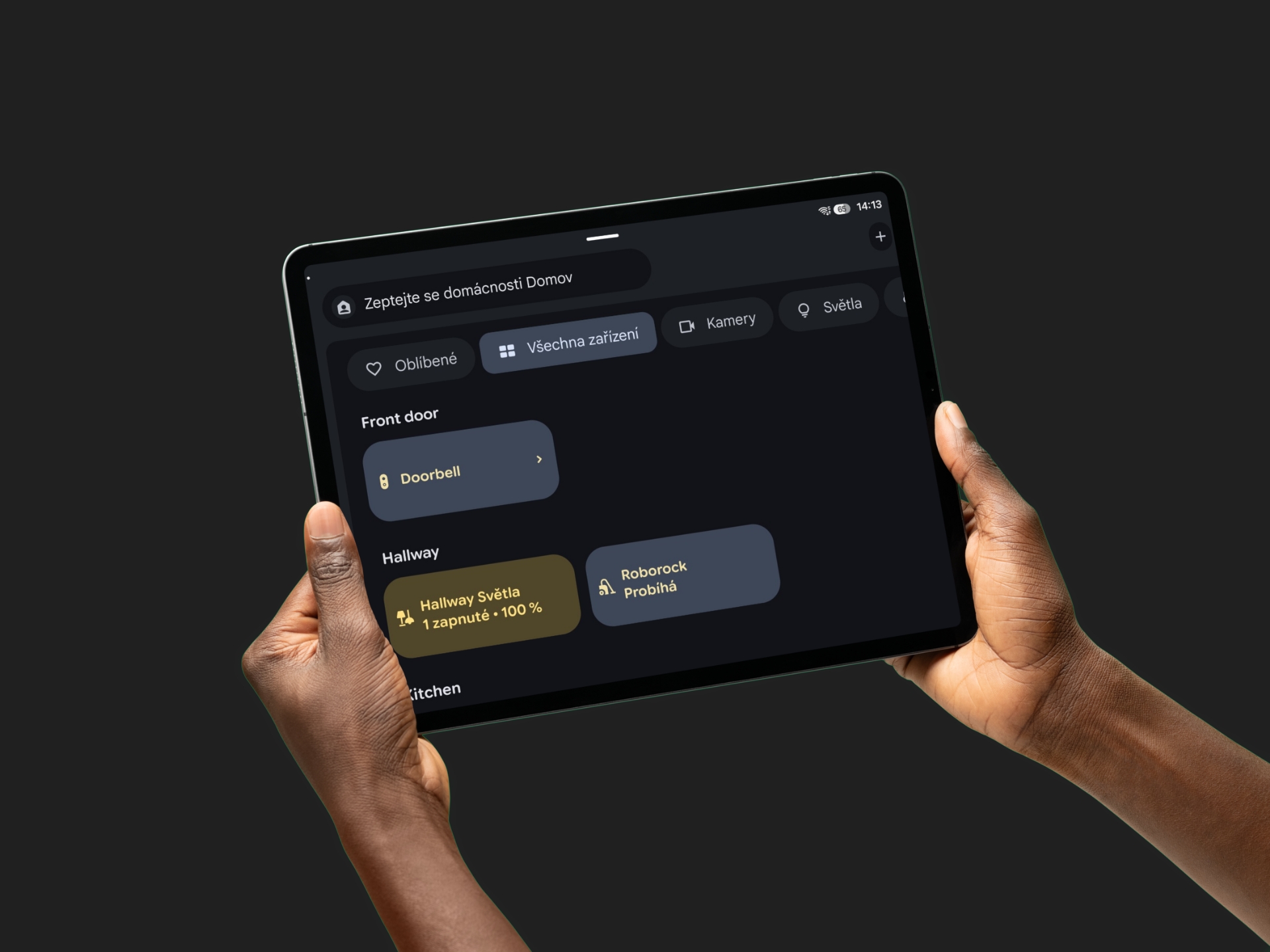 Ruce drží tablet s aplikací chytré domácnosti Google Home, zobrazuje zařízení a světla na tmavém pozadí.